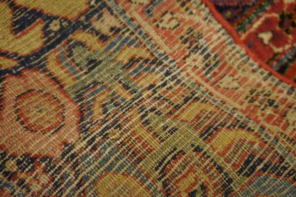 Tight flatweave pattern featuring interlocking geometric motifs colored tan, dark blue, green, and rust red.