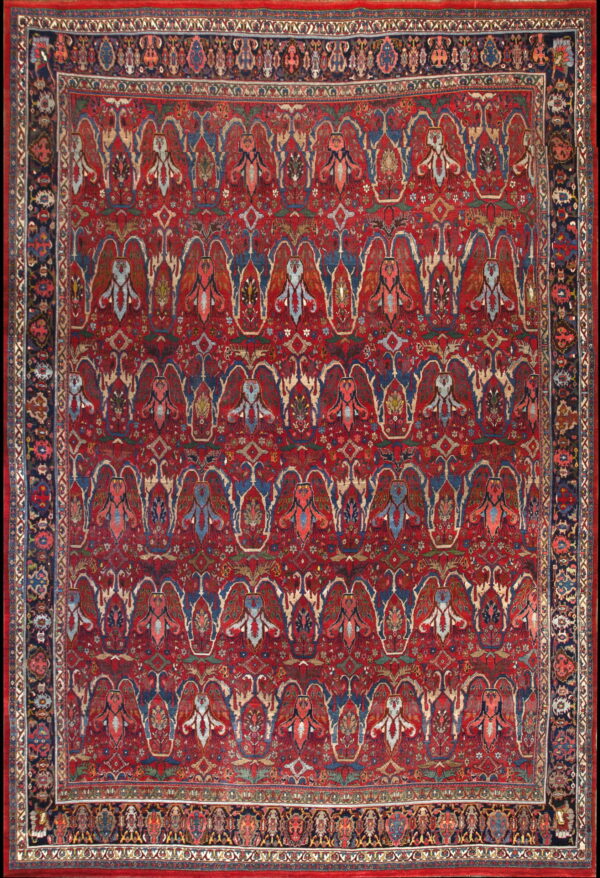 Traditional red rug with an all-over pattern of stylized multicolored floral motifs and a wide dark blue border.