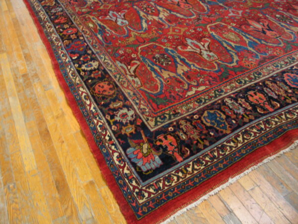 Red patterned area rug with a detailed navy border displayed on golden hardwood planks.
