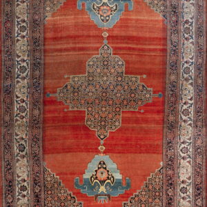 Low pile rug with rust field, stepped blue medallion, and ornate floral borders in cream and navy.