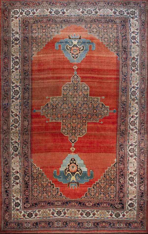 Low pile rug with rust field, stepped blue medallion, and ornate floral borders in cream and navy.