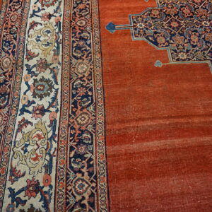 Rust field rug contrasts with a navy and cream multi-border design on visible hardwood floors.