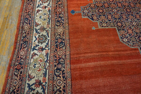 Rust field rug contrasts with a navy and cream multi-border design on visible hardwood floors.
