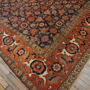 Intricate navy blue and orange floral rug corner rests on weathered gray wood planks.