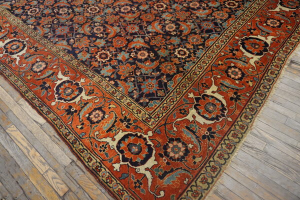 Intricate navy blue and orange floral rug corner rests on weathered gray wood planks.