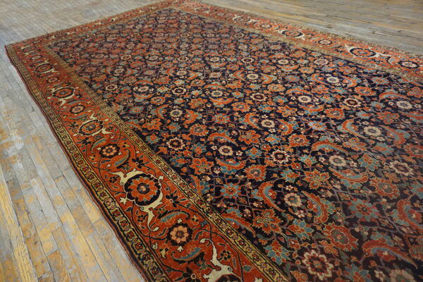 A densely patterned rug with a dark field and rust border rests on pale, weathered wood planks.