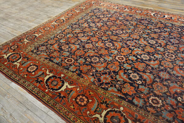 Ornate navy and rust-colored rug with complex floral patterns placed diagonally on gray wood floors.