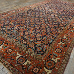 A large navy and terracotta rug with a detailed floral pattern lies on gray hardwood floors.