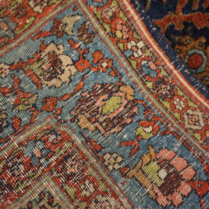 Intricate traditional rug pattern featuring tight knots and worn texture in teal, rust, navy, and pink.
