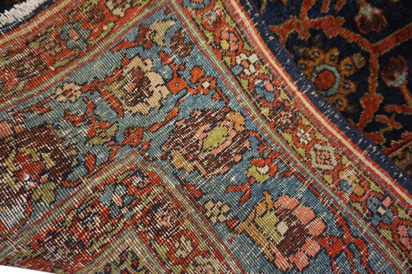 Intricate traditional rug pattern featuring tight knots and worn texture in teal, rust, navy, and pink.