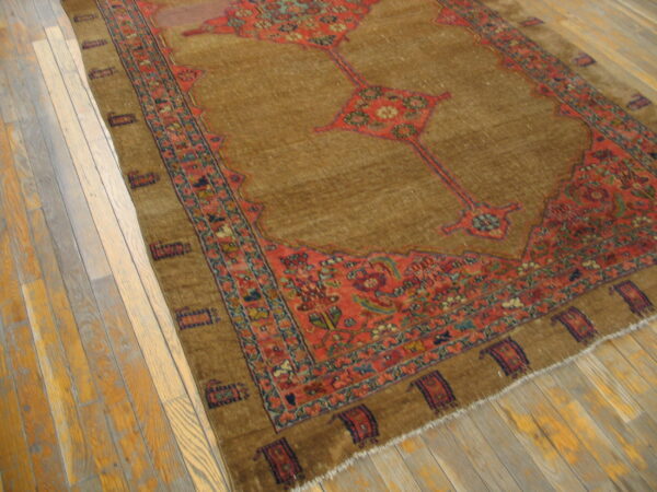 Traditional brown rug with red floral medallions and borders sits on rustic wood plank flooring.