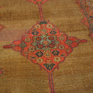 Distressed brown rug with a coral and blue floral medallion, featuring a detailed border on wood floor.