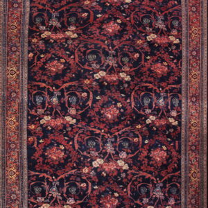 Dark blue rug with a dense pattern of red florals and vines, featuring a detailed multi-colored border.