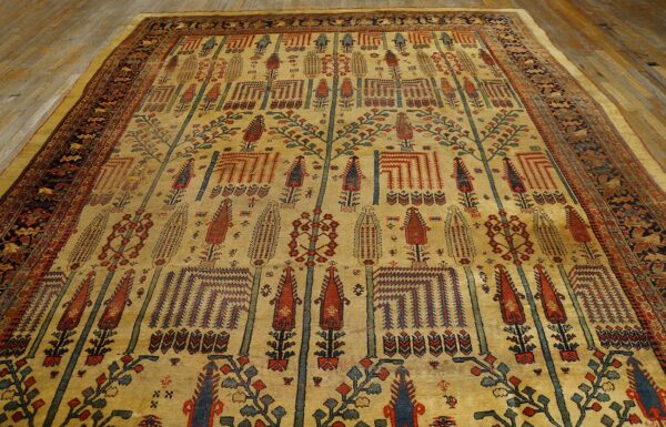A large golden rug with detailed red, blue, and green vertical tree patterns is displayed on wood planks.