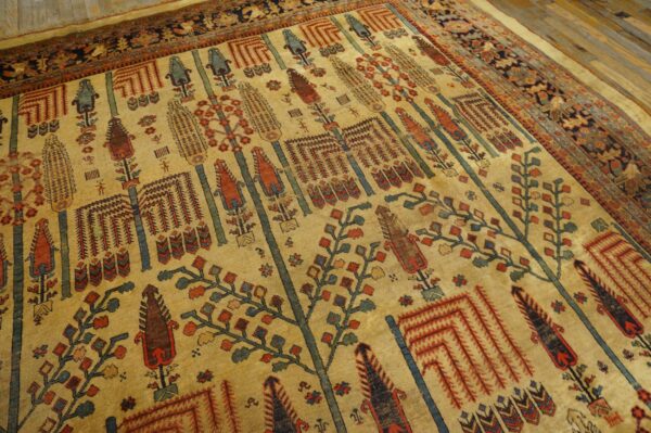 Close-up of a gold field rug with stylized red, blue, and green vertical tree patterns on wood flooring.