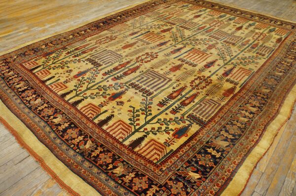 Golden yellow rug featuring a repeating stylized tree pattern bordered by dark navy animal and floral motifs.