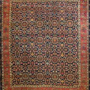 Dark blue rug displaying a repeating multicolored floral lattice design and a wide red botanical border.