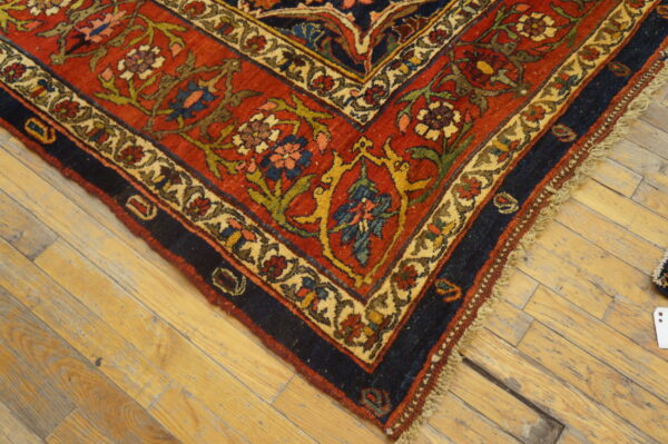 Ornate red, navy, and cream floral rug border resting on worn, light-colored wooden planks.