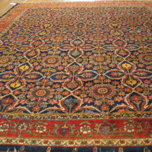 Large rug with a complex navy, red, and gold floral medallion pattern on a light wood floor.