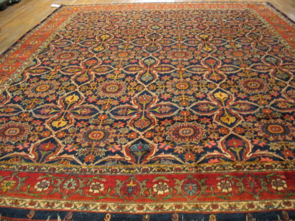 Large rug with a complex navy, red, and gold floral medallion pattern on a light wood floor.