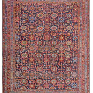 A densely patterned navy rug featuring repeating red, blue, green, and gold geometric and stylized motifs.