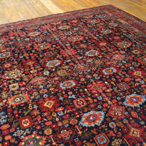 Navy traditional rug with dense red, blue, and multicolor geometric patterns on light wood flooring.