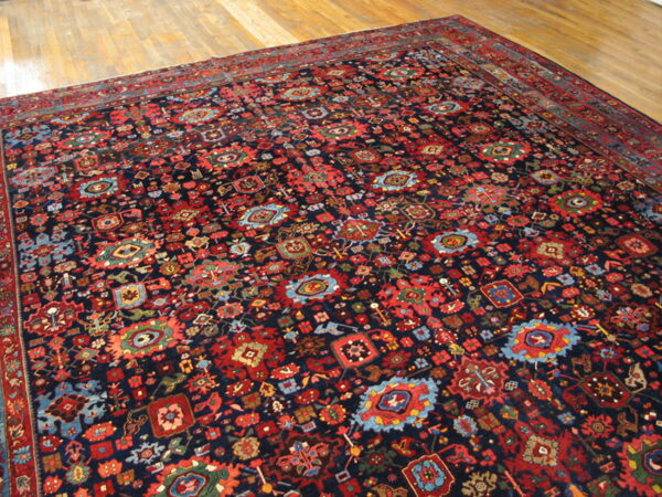 Navy traditional rug with dense red, blue, and multicolor geometric patterns on light wood flooring.