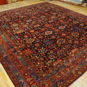 Dark blue rug featuring dense traditional red and multi-colored patterns on a light wood floor.