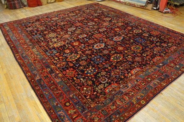 Dark blue rug featuring dense traditional red and multi-colored patterns on a light wood floor.