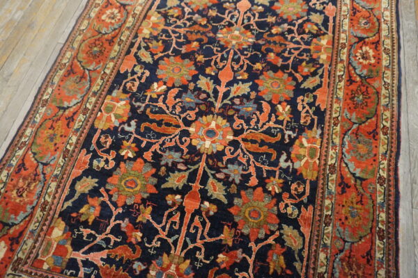 Intricate navy and rust floral rug with multi-colored accents rests on light gray hardwood flooring.