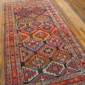 Runner rug featuring red, blue, gold, and green geometric diamonds rests on glossy wood flooring.