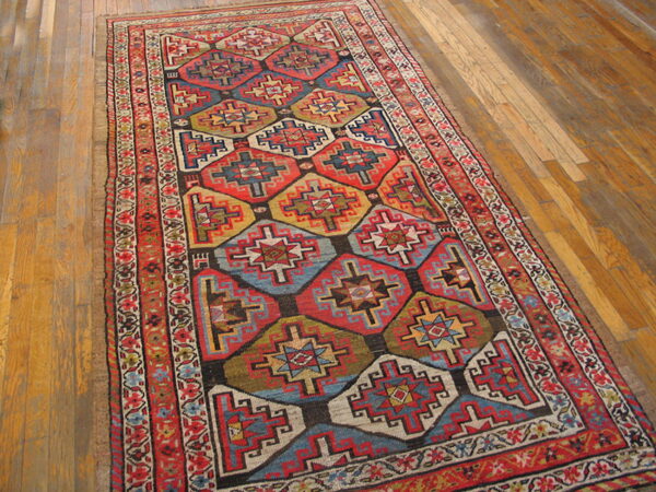 Runner rug featuring red, blue, gold, and green geometric diamonds rests on glossy wood flooring.