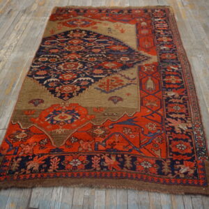 Red and navy geometric-patterned rug with a tan field shown on rustic gray wood flooring.
