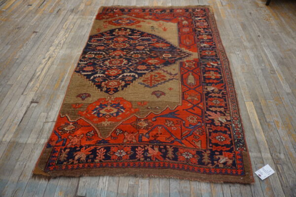 Red and navy geometric-patterned rug with a tan field shown on rustic gray wood flooring.