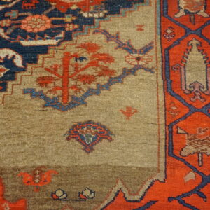 Geometric rug detail showing a tan field patterned with red motifs, framed by navy blue and bright orange borders.