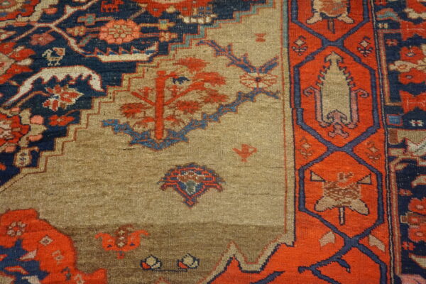 Geometric rug detail showing a tan field patterned with red motifs, framed by navy blue and bright orange borders.