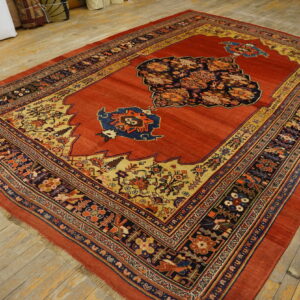 Red rug with an elaborate multicolored medallion and patterned borders covers light-toned wood flooring.