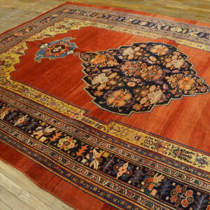 Terracotta and navy rug with an ornate central medallion and multicolored borders sits on light wooden flooring.