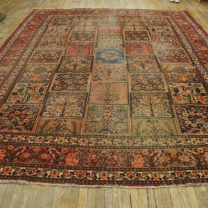 Muted rectangular rug with a complex, grid-like pattern featuring floral and tree motifs on distressed wood flooring.