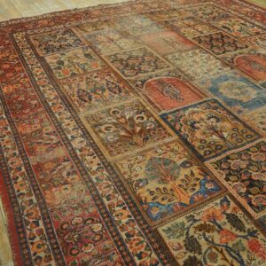 Multicolored paneled rug with floral and tree motifs lies on distressed yellow-toned hardwood flooring.