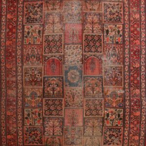 Faded red and navy rug featuring a floral grid panel design with tree motifs and a wide decorative border.