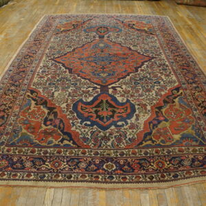 Rust and navy central medallion rug with dense botanical patterns lying on distressed wood floorboards.