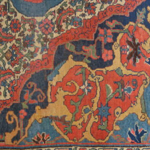 Detailed view of a low-pile rug featuring red, dark blue, beige, and yellow stylized animals and flowers.