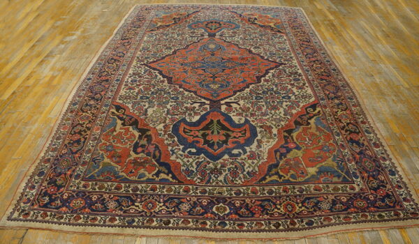 Intricate patterned rug in deep blue and terracotta against a cream background, displayed on worn hardwood.