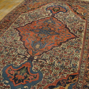 Rug with complex floral design, featuring a large rust and navy medallion, on light plank flooring.