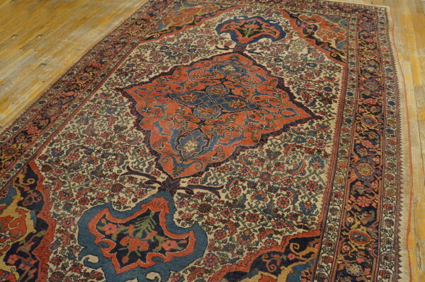 Rug with complex floral design, featuring a large rust and navy medallion, on light plank flooring.