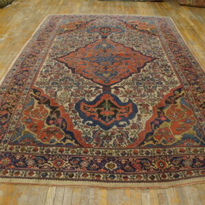 Large traditional rug with blue and orange medallion sits on distressed yellow hardwood flooring.