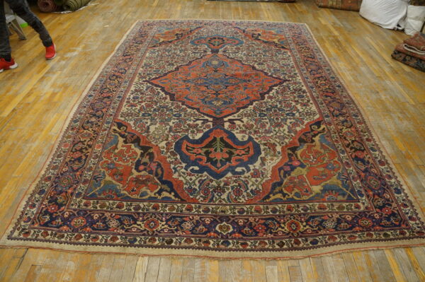 Large traditional rug with blue and orange medallion sits on distressed yellow hardwood flooring.