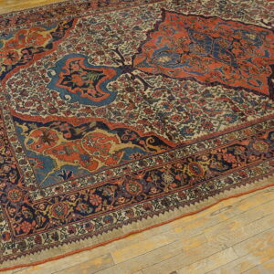 Blue and orange traditional rug with an intricate floral field sits on distressed light wood floors.
