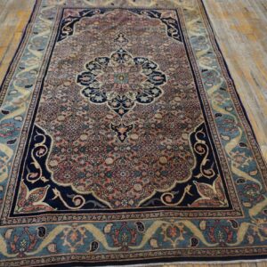 A traditional navy, coral, and teal rug with an intricate medallion design lies on distressed wooden flooring.